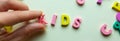 female hand makes the word kids from wooden multicolored letters. educational games. selective focus