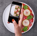 Female hand making a photo of Italian beef carpaccio with sliced zucchini Royalty Free Stock Photo