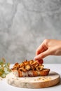 Female hand making a toast with roasted chanterelles, on marble countertop. Fried wild mushrooms. Generative AI