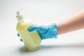 Female hand in medical latex blue signet holds a yellow bottle with liquid soap on a white background. Horizontal orientation Royalty Free Stock Photo
