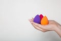 Female hand with nice manicure holding purple, pink and orange beauty blenders. Space for text Royalty Free Stock Photo