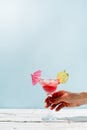 female hand with nice red manicure holding fresh summer cocktail with strawberry, lime and ice cubes on blue background Royalty Free Stock Photo