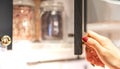 The female hand open door on white kitchen cupboard with kitchenware supplies, standing in apartment with modern interior Royalty Free Stock Photo