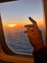 Female hand opening an airplane window at sunset. People traveling by plane, transportation, vacation concept Royalty Free Stock Photo