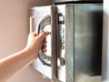 Female hand opens an old microwave oven at home