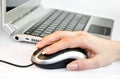 Female hand operating computer mouse in front of laptop Royalty Free Stock Photo