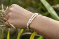 Hand outdoor touching plants with pearl and hematite bracelet