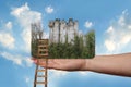 Female hand outstretched against beautiful summer landscape, blue sky with clouds, ancient castle, a wooden staircase in the palm Royalty Free Stock Photo