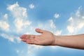 Female hand outstretched against beautiful summer landscape, blue sky with clouds, concept of transcendence, infinity, height, the