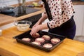 Female hand overlays stuffing theminced meat or meatballs laying on a black baking tray. Process of cooking