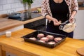 Female hand overlays stuffing theminced meat or meatballs laying on a black baking tray. Process of cooking