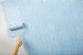 Female hand paints wall with paint roller