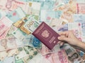 Female hand with passport and money of south-east Asia and American hundred dollar bill. Currency Royalty Free Stock Photo