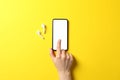 Female hand, phone with empty screen and headphones on yellow background Royalty Free Stock Photo