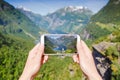 Female hand with phone photographing Geiranger fjord, Norway