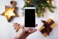 Female hand with a phone takes pictures of New Year`s decorations and fir branches