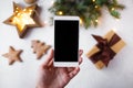 Female hand with a phone takes pictures of New Year`s decorations and fir branches