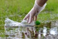 Female hand pick up plastic bottle from the puddle of water in the forest.