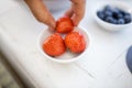 Female hand picking a strawberry from small white plate Royalty Free Stock Photo