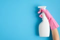 Female hand in pink glove holding cleaning spray bottle on blue background. House cleaning or housekeeping concept Royalty Free Stock Photo