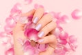 Female hand with pink nail design. Female hand hold pink rose petals. Glitter pink nail polish manicure on pink background Royalty Free Stock Photo