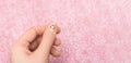 Female hand with pink nail design. Smiling face nail art decoration on a thumb. Woman hand on glitter pink background