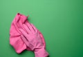 Female hand in a pink rubber glove holds a pink cleaning rag on a purple background, close up Royalty Free Stock Photo