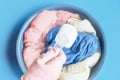 Female hand in a pink rubber glove holds scoop with washing powder on a late basin with soaked laundry on a blue Royalty Free Stock Photo