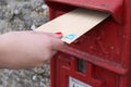A female hand posting a letter in a post box in the UK