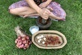 A female hand pounding many kinds of herbs in mortar to make Thai red curry chili paste