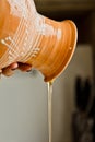 Female hand pouring ceramic ewer oil into a metal bowl. painted in white enamel, a brown earthenware jug close-up vertical. Royalty Free Stock Photo