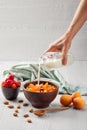 Female hand pouring milk in muesli with apricots and almonds Royalty Free Stock Photo