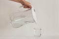 Female hand pouring purified water from a jug