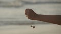 Female hand pouring sea sand through her fingers at sunset against an ocean background. Arm of young woman with sand Royalty Free Stock Photo