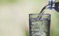 Female hand pouring water from bottle to glass on blur background Royalty Free Stock Photo