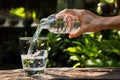 Female hand pouring water from bottle to glass on nature background Royalty Free Stock Photo