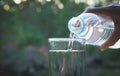 Female hand pouring water from bottle to glass on nature Royalty Free Stock Photo