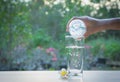 Female hand pouring water from bottle to glass on nature Royalty Free Stock Photo