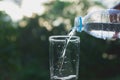 Female hand pouring water from bottle to glass on nature Royalty Free Stock Photo