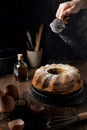 Female hand powdering marble bundt cake