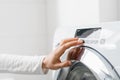 Female hand press button on washing machine indoors Royalty Free Stock Photo