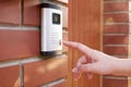 The female hand presses a button doorbell with intercom