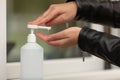 Female hand pressing bottle and pouring alcohol-based sanitize on hands. Disinfection concept. Liquid soap with pumping from