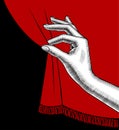 Female hand pulling aside the red curtain on black background