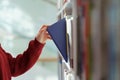 Woman hand picking book from bookshelf in library in university, college, high school or bookshop Royalty Free Stock Photo