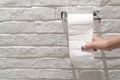 Female hand pulling a white tissue paper from tissue roll in the restroom. Royalty Free Stock Photo