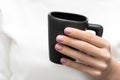 Female hand with purple nail design holding black coffee cup Royalty Free Stock Photo