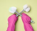 Female hand in purple rubber gloves holds a plastic cleaning brush on green background Royalty Free Stock Photo