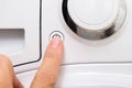 Female hand pushing start stop button of washer, washing machine cycle interraption or starting, beginning