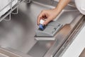 female hand puts dishwasher tablet into open dishwasher machine Royalty Free Stock Photo